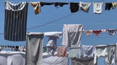 Çamaşır ipine asılmış bir kıyafet. Yakından. Giysiler beyaz, pembe ve siyah.