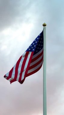 Gri gökyüzünde büyük bir Amerikan bayrağı dalgalanıyor. Amerikan bayrağı. Amerikan bayrağı. Yüksek 4k kalite video