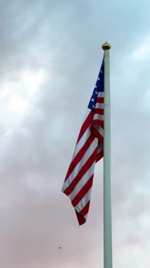 Gri gökyüzünde büyük bir Amerikan bayrağı dalgalanıyor. Amerikan bayrağı. Amerikan bayrağı. Yüksek 4k kalite video