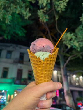 Şehrin arka planında dondurma külahı. Dondurmayı elle tutan adam. Yüksek kalite fotoğraf