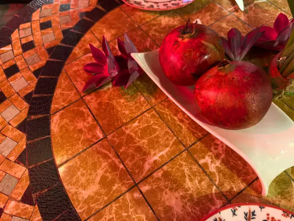 İki kırmızı nar içeren beyaz bir tabakla bir masa. Narlar tabağın üstüne konur ve tabağın ortasına yerleştirilir.