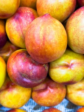 Şeftali, bir demet şeftali üst üste yığılmış. Hepsi farklı boyutlarda ve renklerde.