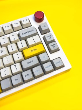 Parlak sarı arka planda Enter tuşuna sahip beyaz mekanik klavye, minimalizm, klavye tuşları. Sol altta sarı tuş olan bir klavye. Klavyede büyük harf kilit tuşu ve kaydırma tuşu var.