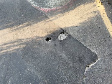 Sarı uyarı bandı ve kırık asfalt ile çevrili bozuk bir yol. Sarı ve siyah bir bant yolda. Kaset yerde.