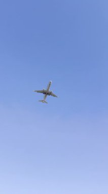 Büyük beyaz bir uçak açık mavi gökyüzüne karşı yere yakın uçar. Gökyüzünde bir uçak uçuyor. Gökyüzü açık ve mavi