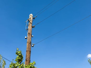 Sokak tahtası, kazık tahtadan yapılmış, telefon direği, direkteki kablolar. Üzerinde kablolar olan uzun tahta bir direk. Kutup mavi gökyüzünün ortasında.