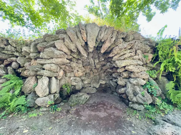 Küçük bir mağara, taştan yapılmış bir mağara, terk edilmiş eski bir yer. Ortasında delik olan küçük bir taş yapı. Delik kayalarla çevrili. Yapı bir ormanda bulunuyor.