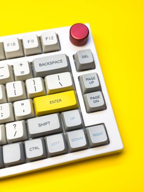 Parlak sarı arka planda Enter tuşuna sahip beyaz mekanik klavye, minimalizm, klavye tuşları. Sol altta sarı tuş olan bir klavye. Klavyede büyük harf kilit tuşu ve kaydırma tuşu var.