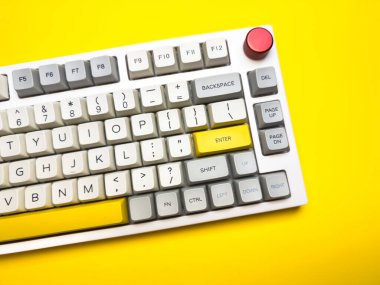 Parlak sarı arka planda Enter tuşuna sahip beyaz mekanik klavye, minimalizm, klavye tuşları. Sol altta sarı tuş olan bir klavye. Klavyede büyük harf kilit tuşu ve kaydırma tuşu var.
