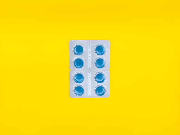 Синяя таблетка сидит на белом фоне. Таблетка квадратной формы и имеет синий центр. копировальное пространство, flay, вид сверху