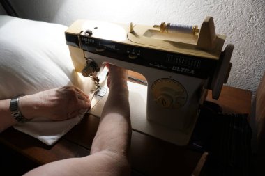 Yaşlı bir kadın dikiş makinesine yastık dikiyor. Yaşam tarzı, hobiler, el sanatları ve ev projeleri için mükemmel..