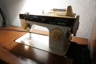 Tahta bir masanın üzerinde duran dikiş makinesinin ayrıntılı görüntüsü. Zanaat, DIY ve ev projesi görselleri için ideal.