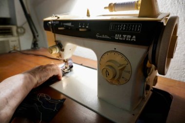Yaşlı bir kadın dikiş makinesine yastık dikiyor. Yaşam tarzı, hobiler, el sanatları ve ev projeleri için mükemmel..