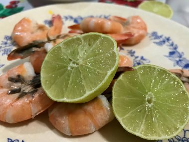 Yanında yarım limon olan taze pişmiş karides yakın plan, basit bir tabakta servis edilir..