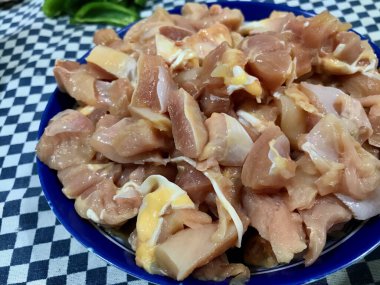 Pişmemiş tavuk parçaları, pişirilmeye ya da baharata hazır mavi plastik bir kaseye konur..