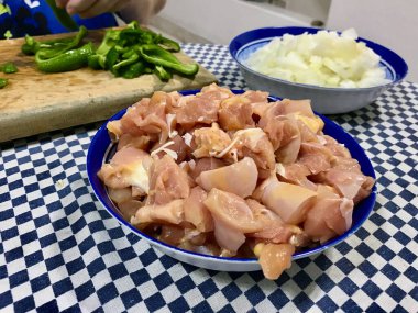 Pişmemiş tavuk parçaları, pişirilmeye ya da baharata hazır mavi plastik bir kaseye konur..