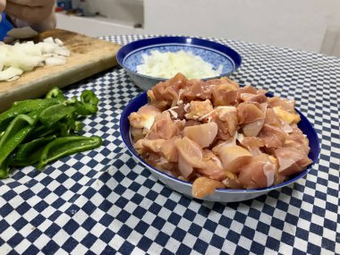 Pişmemiş tavuk parçaları, pişirilmeye ya da baharata hazır mavi plastik bir kaseye konur..