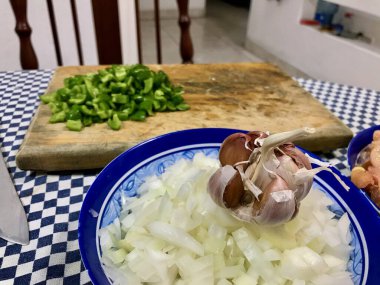 Çiğ tavuk, doğranmış soğan, yeşil biber ve sarımsaklı karanfil de dahil olmak üzere çeşitli taze yemek malzemeleri..
