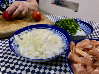 Çiğ tavuk, doğranmış soğan, yeşil biber ve sarımsaklı karanfil de dahil olmak üzere çeşitli taze yemek malzemeleri..