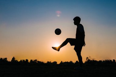Çocukların dışarıda futbol oynayarak eğlendiği bir spor. Toplumun kırsal kesimlerinde alacakaranlık günbatımı gökyüzünün altında. Kopyalama alanı ile resim.