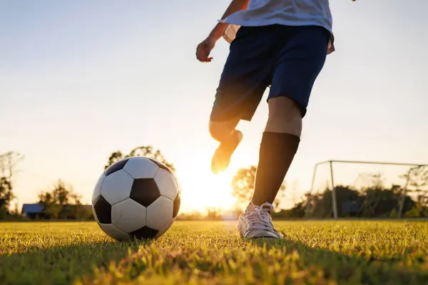 Çocukların dışarıda futbol oynayarak eğlendiği bir spor. Toplumun kırsal kesimlerinde alacakaranlık günbatımı gökyüzünün altında. Kopyalama alanı ile resim.
