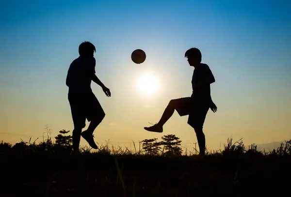 Çocukların dışarıda futbol oynayarak eğlendiği bir spor. Toplumun kırsal kesimlerinde alacakaranlık günbatımı gökyüzünün altında. Kopyalama alanı ile resim.