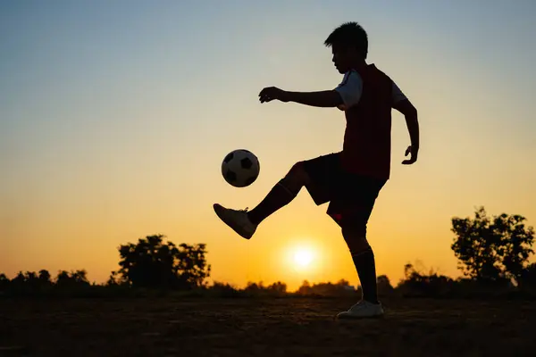 Çocukların dışarıda futbol oynayarak eğlendiği bir spor. Toplumun kırsal kesimlerinde alacakaranlık günbatımı gökyüzünün altında. Kopyalama alanı ile resim.