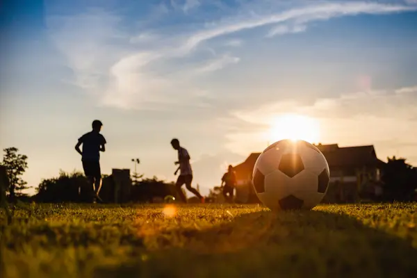 Çocukların dışarıda futbol oynayarak eğlendiği bir spor. Toplumun kırsal kesimlerinde alacakaranlık günbatımı gökyüzünün altında. Kopyalama alanı ile resim.