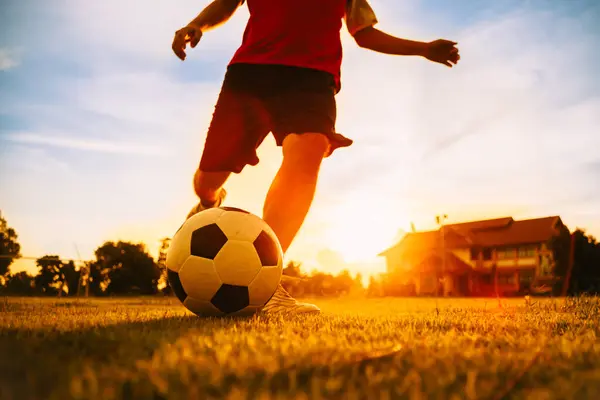 Çocukların dışarıda futbol oynayarak eğlendiği bir spor. Toplumun kırsal kesimlerinde alacakaranlık günbatımı gökyüzünün altında. Kopyalama alanı ile resim.