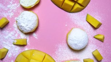 Tatlı Mochi, mango meyveli ve pembe arka planda 360 derecelik dönüş, yakın çekim. Geleneksel Japon pirinç keki