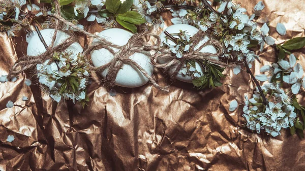 White Easter eggs with flowers on golden background, close up. Concept of Easter Sunday,  religious traditions and symbolism