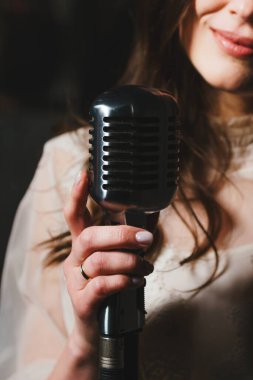 Modern mikrofon tutan tanınmayan genç bayan şarkıcı, yakın plan. Şarkı söyleyen kadın. Yüzü olmayan kişi. Canlı performans veya konser kavramı