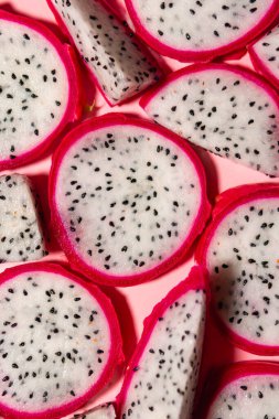 Taze beyaz pitaya dilimleri ya da pembe arka planda ejderha meyvesi, düz. Egzotik tropikal ve vejetaryen gıda kavramı.