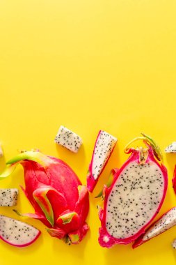 Taze beyaz pitaya dilimleri ya da sarı arka planda ejderha meyvesi, düz. Egzotik tropikal ve vejetaryen gıda kavramı.