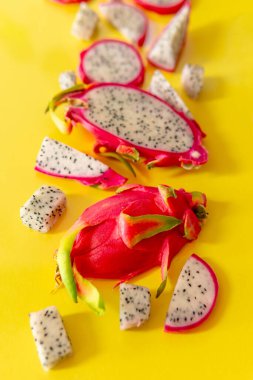 Taze beyaz pitaya dilimleri ya da sarı arka planda ejderha meyvesi, düz. Egzotik tropikal ve vejetaryen gıda kavramı.