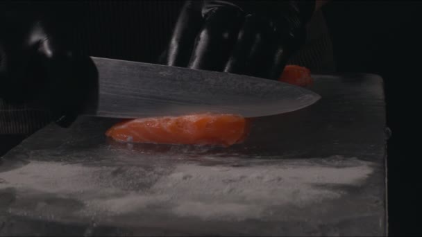新鮮な鮭の切り身を調理する準備シェフのクローズアップ 黒の背景 スローモーション 氷のブロック上の生の魚 — ストック動画