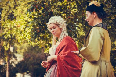 Tarihi Barok kıyafetleri giymiş iki kadının portresi. Eski moda saç stili, açık havada. Lüks ortaçağ elbisesi