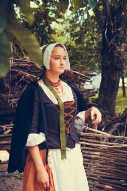 Esmer kadın portresi. Tarihi Barok kıyafetler giymiş. Eski moda saç stili, açık havada. Orta sınıf ortaçağ elbisesi