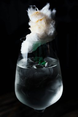 Alcoholic drink. A cocktail with elite alcohol on dark black background, close-up. Concept of  nightlife and exotic drinks.