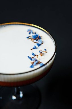 Alcoholic drink. A cocktail with elite alcohol on dark black background, close-up. Concept of  nightlife and exotic drinks.