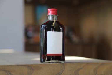 İzole edilmiş soğuk kahve ya da içecek şişesi. Doğal ışıkta, ahşap zeminde ve güzel bir mekanda çekilmiş. İleti veya marka için boş boşluk