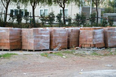 Şantiyedeki turuncu kil blok, içi boş tuğla, palet istiflenmiş, gerilmiş.