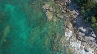 Yukarıdan aşağıya deniz kıyısında. Dalgalar kayalıklara çarpıyor. Güneşli yaz günlerinde güzel bir deniz yüzeyi Kata sahilinde inanılmaz bir deniz manzarası, Phuket