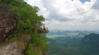 Genç arkadaşlar, Tayland 'ın Krabi Eyaleti' ndeki Ejderha Tepesi 'nin tepesindeki kayanın kenarında Khao Ngon Nak' ta oturuyorlar. Hava aracı görünümü
