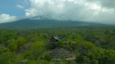 Bali 'de yemyeşil ve dağlarla çevrili göz kamaştırıcı bir kulübe bulutlu bir gökyüzünün altında sakin bir manzara sergiliyor..