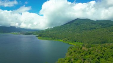 İkiz Göl 'ün sakin manzarası, yemyeşil alanlar, gökyüzünü yansıtan berrak sular ve bulutlarla kaplı görkemli dağlar..