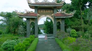 Vietnam 'da yemyeşil yemliklerle çevrili güzel tasarlanmış bir Budist tapınağının girişinde duran bir adamın hava görüntüsü..