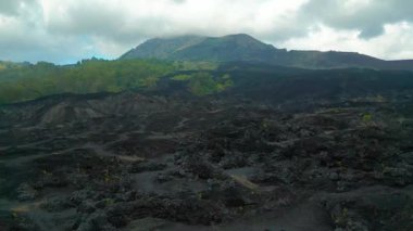 Batur Dağı 'nı çevreleyen geniş siyah lav tarlalarını gösteren hava manzarası Bali' deki engebeli volkanik araziyi vurguluyor..