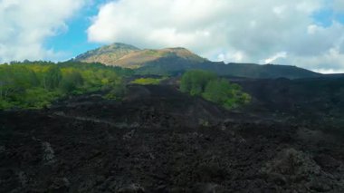 Bali 'deki Batur Dağı' nın havadan görünüşü bulutlu bir gökyüzü altında yemyeşil yemyeşil ve dramatik siyah lav alanları sergiliyor..