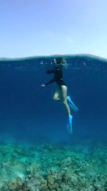 Maldivler 'de bir kişi kısmen şnorkel teçhizatıyla dalıp, mercan resifini göstererek su altında yüzüyor..